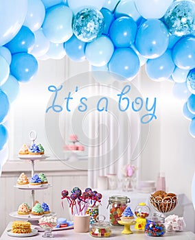 Baby shower party for boy. Tasty treats on table in room with balloons