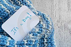 Baby shower `It`s a boy`, announcement card on cozy woolen blue blanket and space for text. New arrival in the family