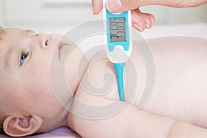 Baby sick with measuring electric thermometer. Child fever ill.