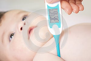 Baby sick with measuring electric thermometer. Child fever ill.
