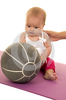 Baby sit on matt with medicine ball in front of her