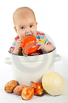 Baby sitting in the big saucepan with vegetables.