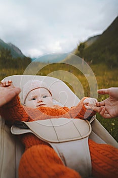 Baby sitting in bouncer family parents holding child hands mo