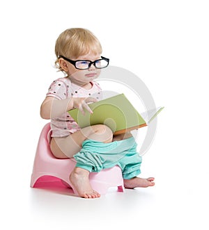 Baby sitting on chamberpot with book