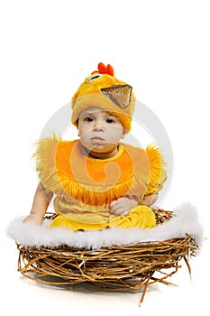 Baby sitting in nest in chicken costume