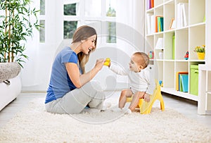 Baby sitting on potty and playing with smiling beautiful mother