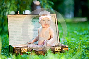 Baby sitting in vintage suitcase in garden