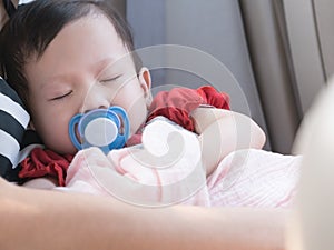 Baby sleep in car with pacifier in mouth.
