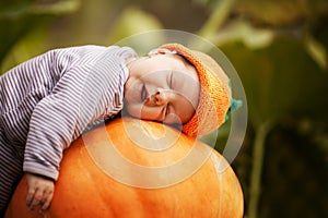 Baby sleeping on big pumpkin