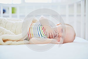 Baby sleeping in co-sleeper crib attached to parents ` bed