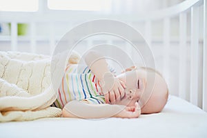 Baby sleeping in co-sleeper crib attached to parents` bed