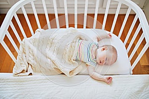 Baby sleeping in co-sleeper crib attached to parents` bed