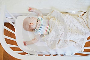 Baby sleeping in co-sleeper crib attached to parents` bed