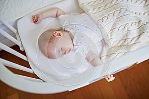 Baby sleeping in co-sleeper crib attached to parents` bed