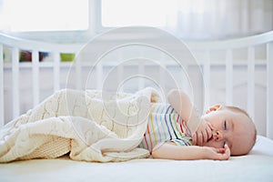 Baby sleeping in co-sleeper crib attached to parents` bed