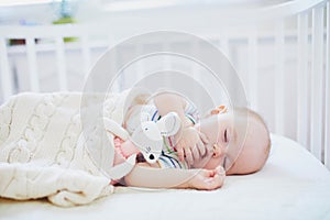 Baby sleeping in co-sleeper crib attached to parents` bed