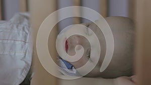 baby sleeping in crib face close-up with closed eyes long lashes hands up lying