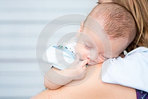 Baby sleeping on his mother`s shoulder