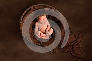 Baby sleeping in old wooden bowl