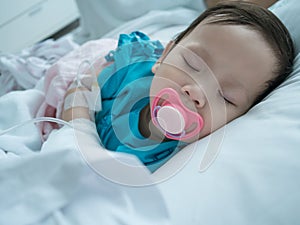 Baby sleeping in sickbed in hospital in recieving intravenous.