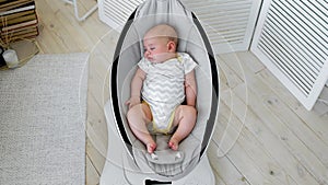 Baby sleeps in a rocking chair for children high-tech design in white bedroom