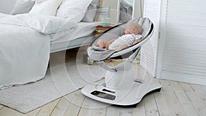 Baby sleeps in a rocking chair for children high-tech design in white bedroom