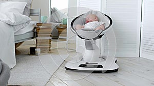 Baby sleeps in a rocking chair for children high-tech design in white bedroom