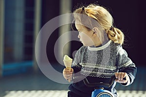 Baby or small boy eating ice cream on toy bike