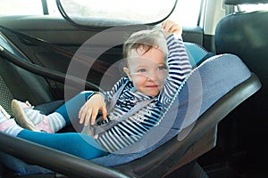 Baby smile in a safety car seat. Safety and security. one year old child girl in blue wear sit on auto cradle. Rules for the Safe