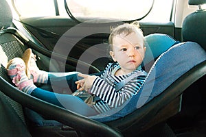 Baby smile in a safety car seat. security. one year old child girl in blue wear sit on auto cradle. Rules for the Safe Transport o