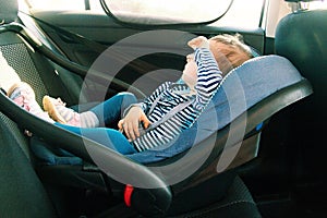 Baby smile in a safety car seat. security. one year old child girl in blue wear sit on auto cradle. Rules for the Safe Transport o