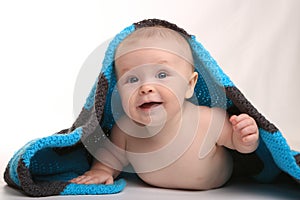 Baby Smiling Lying on Stomach With Blanket on White Background