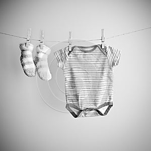 Baby socks and clothes hanging on the clothesline. Background with baby goods with copy space. Black and white photo image.