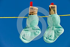 Baby socks on clothesline with yen banknotes