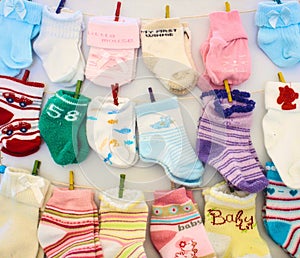 Baby socks and mittens hanging on lines with miniature clothes pegs