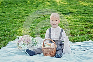 Baby son for Easter in the park, Easter rabbit and basket with eggs in the frame