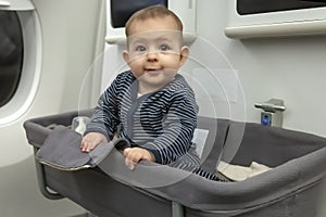 Baby in special bassinet seat in airplane. Have fun during the fly and smile