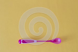 Baby spoon for feeding on a yellow background, yellow