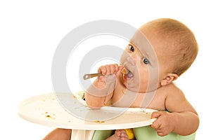 Baby with spoon and food in mouth