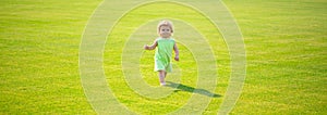 Baby on spring grass field, banner. Baby play in green grass. Child development. Adorable little kid walking in an