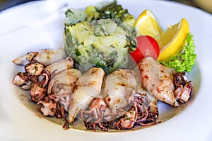 Baby squid and blitva, mashed potatoes with chard, served with lettuce, lemon and tomatoes at a restaurant in Montenegro