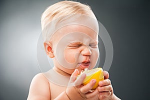 Baby squinting eyes while licking lemon photo