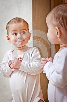 Baby standing against the mirror