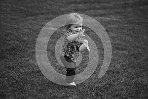 Baby standing barefoot on the green lawn.