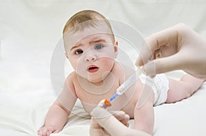 Baby is starring on syringe with immunization vaccine