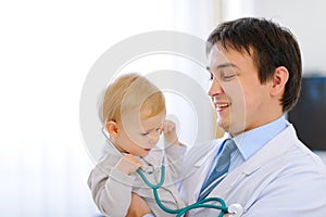 Baby with stethoscope on hands of pediatrician