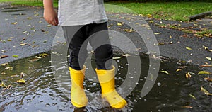 Baby stomping through puddles in yellow rubber boots