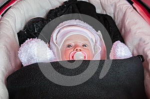 Baby in stroller is dressed and warmly wrapped in freezing winter