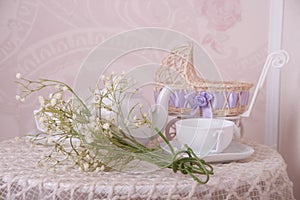 Baby stroller, tea cup and spring bouquet composition