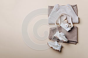 Baby stuff and accessories. Set of knitted clothes - sweater, pants, shoes, wooden camera toy. Baby shower concept